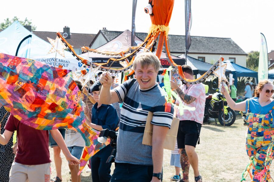several people at the children's parade including people holding a large octopus and a large rainbow fish