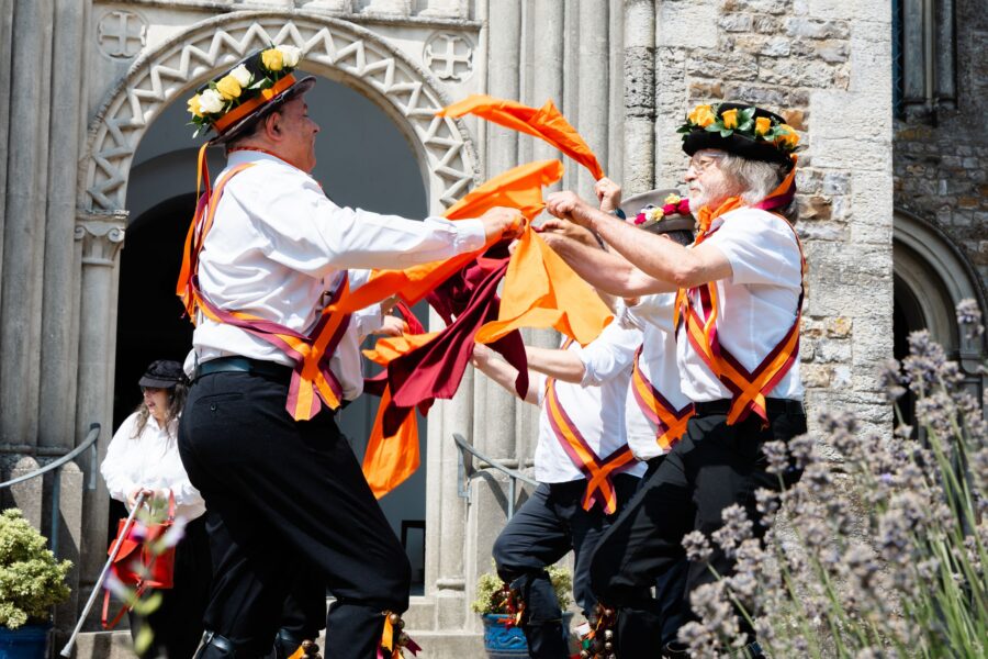 Cynewulf Morris Dancers in white and orange outfits performing outside St Pauls Church