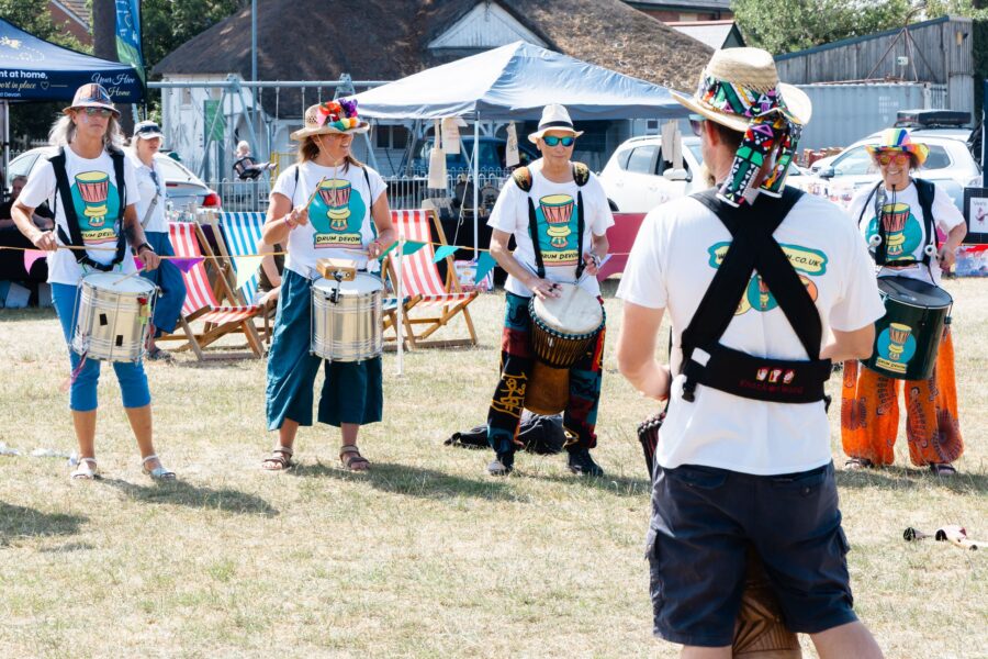 five members of Drum Devon in white branded t-shirts each with a different type of drum