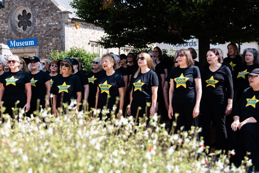 members of the Rock Choir dressed in black and yellow t-shirts with Honiton Museum in the background