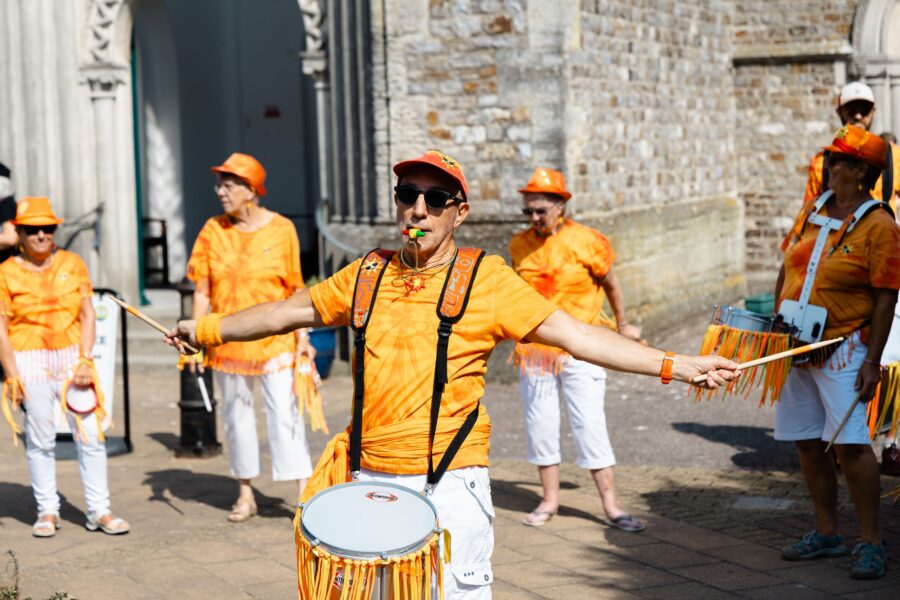 Sunshine Samba drummer arms outstretched with a drumstick in each hand
