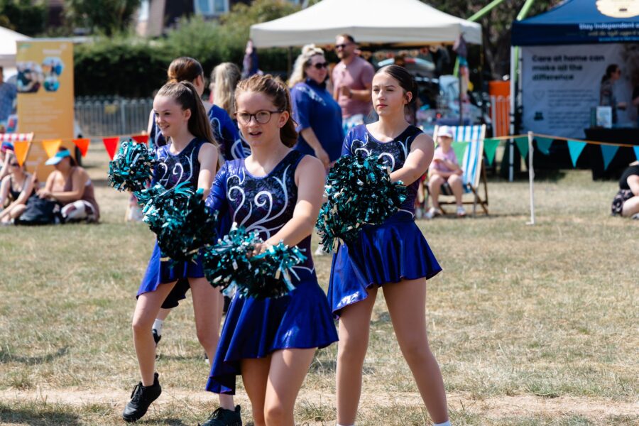 three Honiton Twirlstars Majorettes in dark blue outfits with metallic pom poms