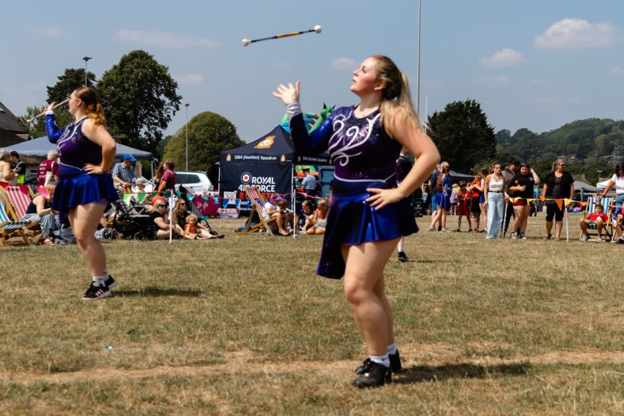 two Twirlstars Majorettes in dark blue outfits throwing batons in the air