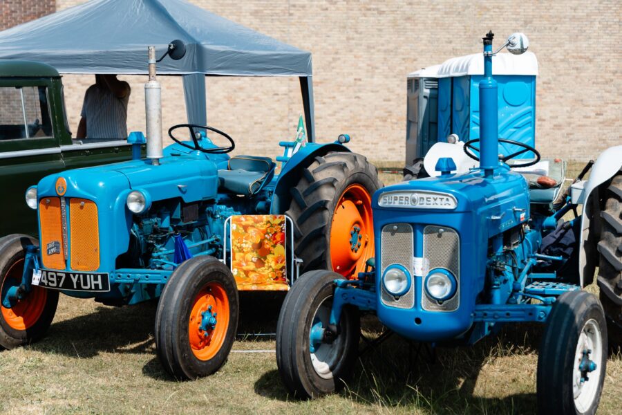 two small vintage tractors one in blue and one in blue with orange wheels and grilles