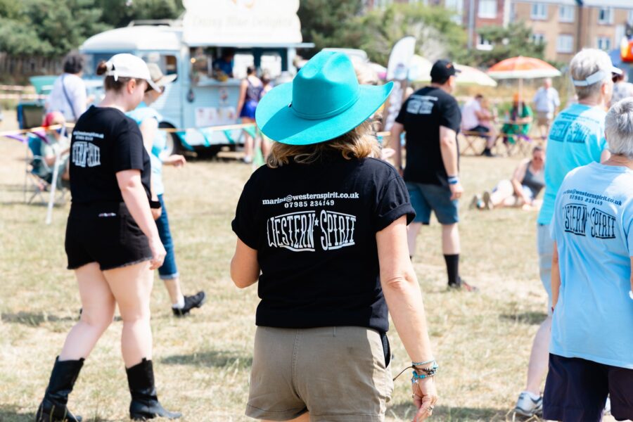 a back view of a member of Western Spirit Line Dance in a black t-shirt and bright blue cowboy hat